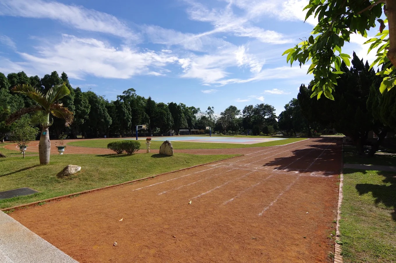 西嶺國小紅土跑道與綠茵運動場,藍天白雲 A red running track and green athletics field under a blue sky