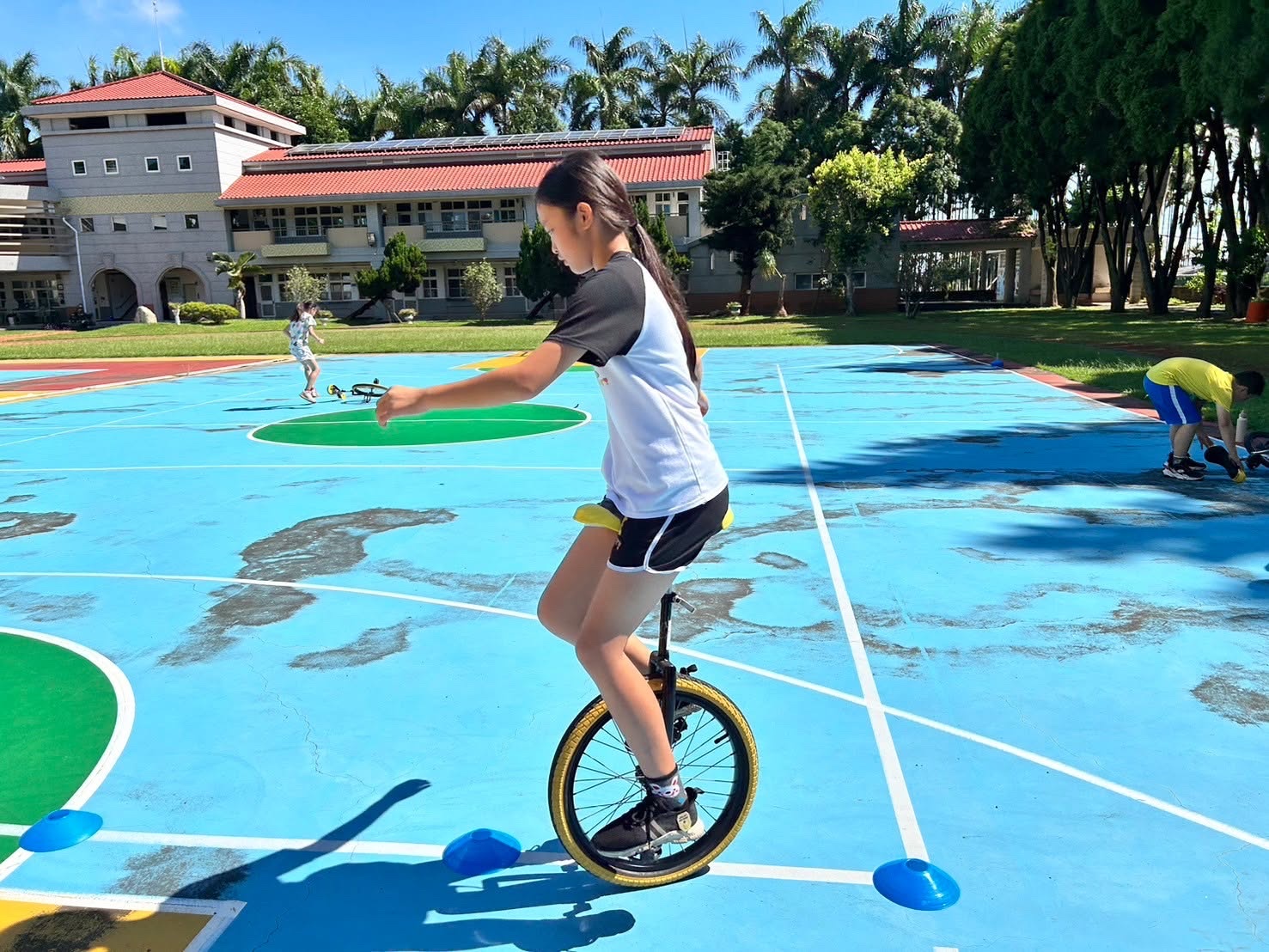 西嶺國小學生在彩色球場上練習獨輪車 A Siling student practices riding a unicycle on the school's colourful court