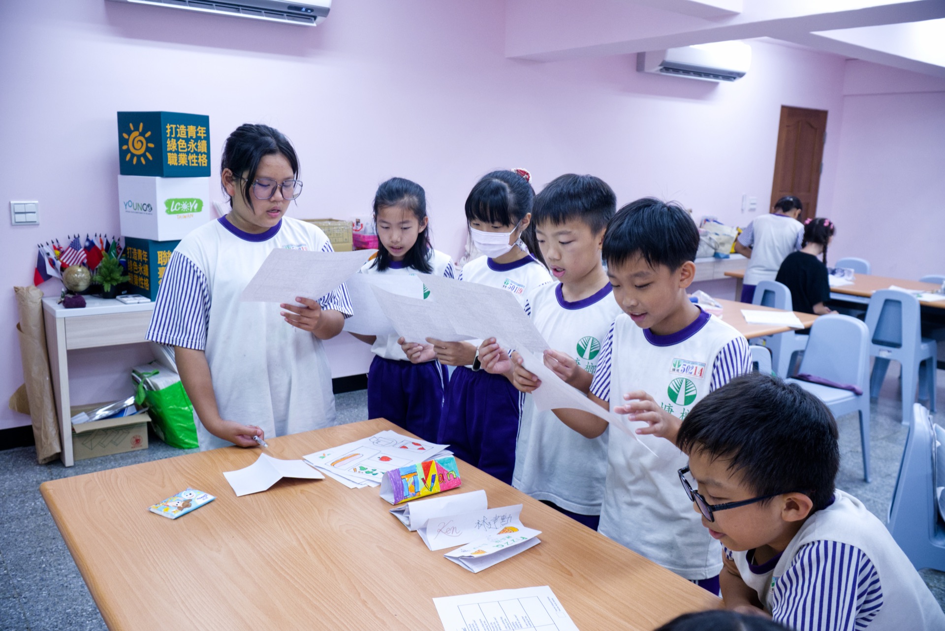 Campers read aloud and discuss worksheets during an SDG-themed English activity