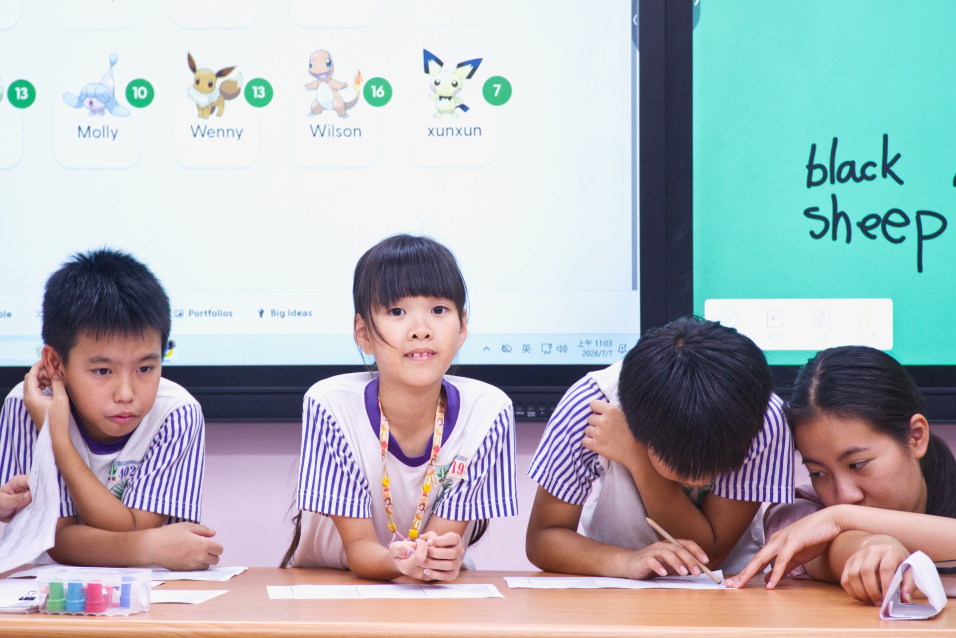 A classroom vocabulary point system on screen beside a Baa Baa Black Sheep reading lesson